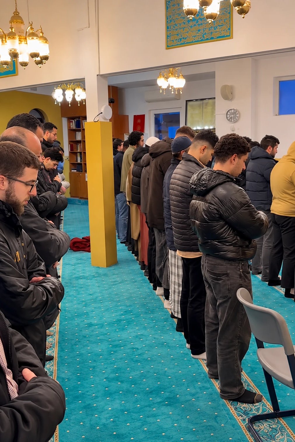 Gemeinschaftsgebet in der Arrahmanmoschee, Gläubige stehen in einer Reihe auf dem türkisen Teppich
